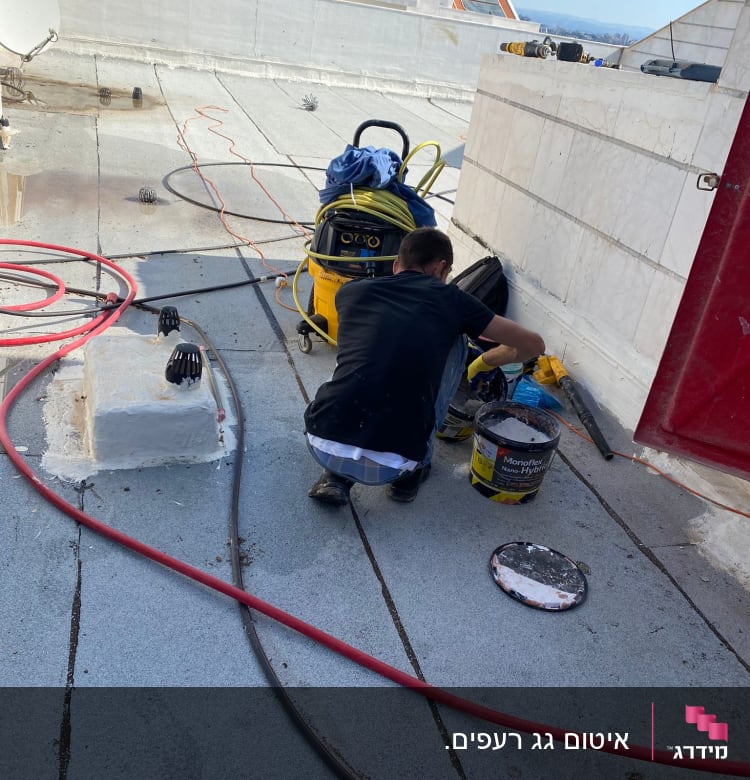 עובד על גג עם דלי וכלי עבודה